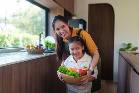 mother and daughter holding fresh vegetables in a kitchen